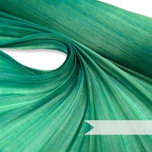 May include: A roll of teal green fabric with a subtle shimmer. The fabric has a textured, woven look and is folded in a spiral shape.
