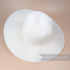 May include: A white sun hat with a wide brim and a slightly rounded crown. The hat is made of a woven straw-like material.