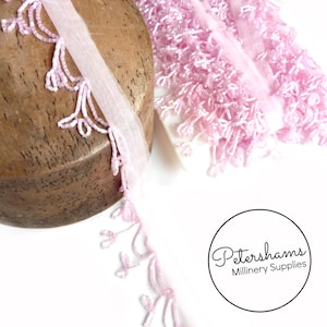 May include: Pink beaded fringe trim with a sheer backing. The fringe is made of small, delicate beads that are strung together to create a flowing, cascading effect. The trim is perfect for adding a touch of elegance to any project.