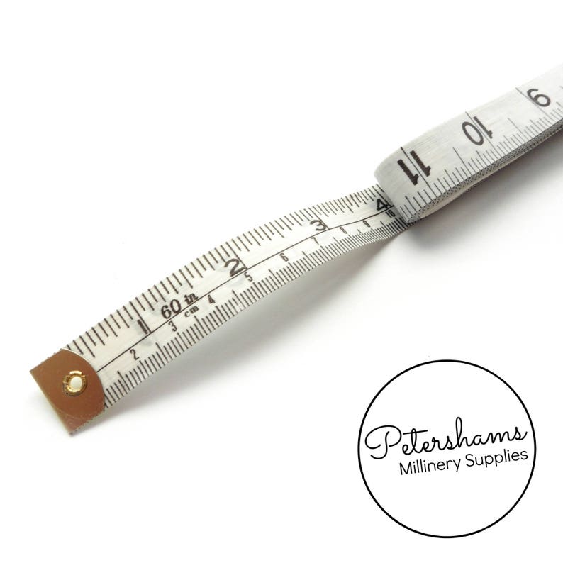 May include: White measuring tape with black markings in inches and centimeters. The tape is 60 inches long and has a brown leather end cap. The tape is curled and the end is visible with the number 11.