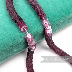 May include: Close-up of a section of a sequin trim in shades of purple. The trim is made of small, round sequins sewn onto a fabric backing. The sequins are a deep, rich purple color, with a slight sheen. The trim is flexible and can be used for various craft projects.