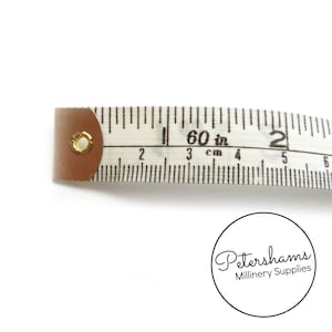 May include: A white tape measure with black markings, showing 60 inches and 150 cm. The tape measure has a metal end with a gold ring.