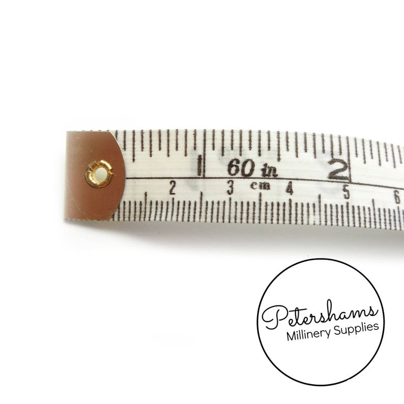 May include: A white tape measure with black markings, showing 60 inches and 150 cm. The tape measure has a metal end with a gold ring.