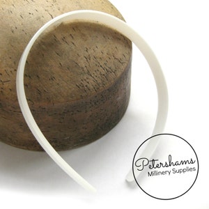 May include: White plastic headband for millinery, displayed on a wooden surface. Petershams Millinery Supplies.