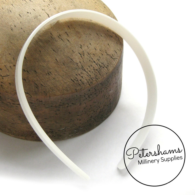 May include: White plastic headband for millinery, displayed on a wooden surface. Petershams Millinery Supplies.