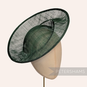 May include: A dark forest green wide-brimmed hat featuring a semi-sheer, woven texture and a structured, rounded crown. The brim is finished with a matching dark green bound edge. The text PETERSHAMS is visible in the lower right corner.