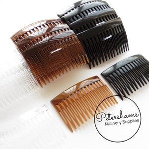 May include: Four plastic hair combs in different colors: clear, brown, and black. The combs are all the same size and shape, with a curved design and a row of teeth on one side. The combs are arranged in a row, with the clear comb at the bottom and the black comb at the top.