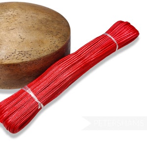 May include: A spool of red Petersham ribbon, a type of grosgrain ribbon, is wrapped around a wooden form. The ribbon is smooth and shiny.