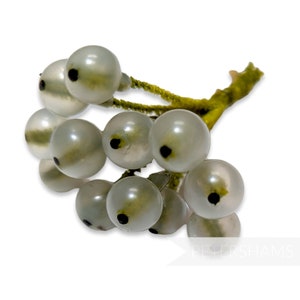 May include: A cluster of white faux berries with black centers on a green stem. The berries are translucent and have a slightly green tint.
