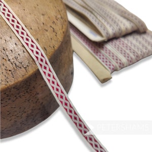 May include: White and red braided trim with a diamond pattern. The trim is wrapped around a wooden spool.