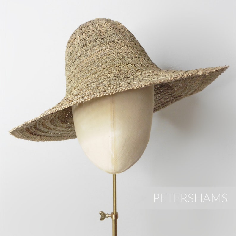 May include: A wide-brimmed straw hat with a crocheted texture. The hat is beige and has a wide, floppy brim.