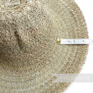 May include: A close-up of a woven straw hat with a diameter of 10 inches. The hat is made of a natural straw material and has a light brown color.