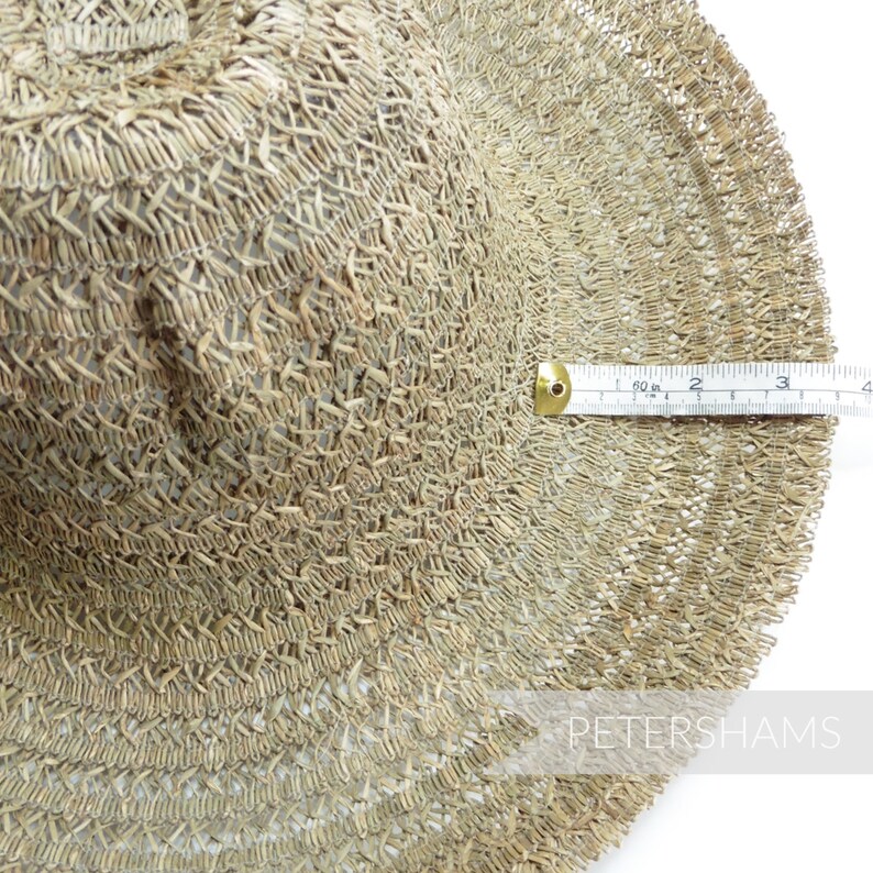 May include: A close-up of a woven straw hat with a diameter of 10 inches. The hat is made of a natural straw material and has a light brown color.