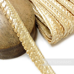 May include: A close-up of a beige woven trim with a scalloped edge. The trim is made of a natural material and has a subtle sheen.