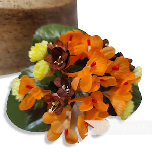 May include: A bouquet of artificial flowers with orange, brown, and yellow petals. The flowers are arranged in a cluster and have a green leafy base.