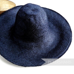 May include: A wide-brimmed, navy blue sun hat made of woven straw. The hat has a slightly rounded crown and a wide, floppy brim. The hat is made by Petershams.