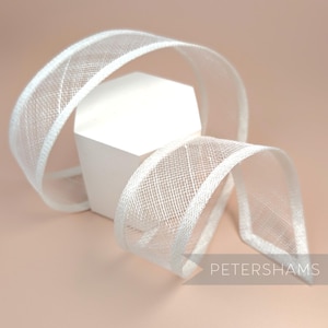 May include: White sheer ribbon with a white satin edge. The ribbon is folded and displayed on a white hexagonal stand.