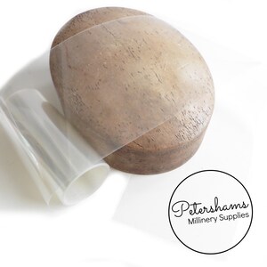 May include: A roll of clear plastic sheeting for millinery, next to a wooden hat block. The sheeting is used for making hat shapes and is available from Petershams Millinery Supplies.