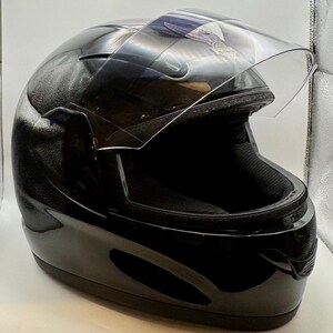 Peut inclure: Casque de moto noir brillant avec une visi&egrave;re transparente relev&eacute;e. Le casque pr&eacute;sente un design profil&eacute; et une surface textur&eacute;e sur le dessus. L'int&eacute;rieur rembourr&eacute; est visible.