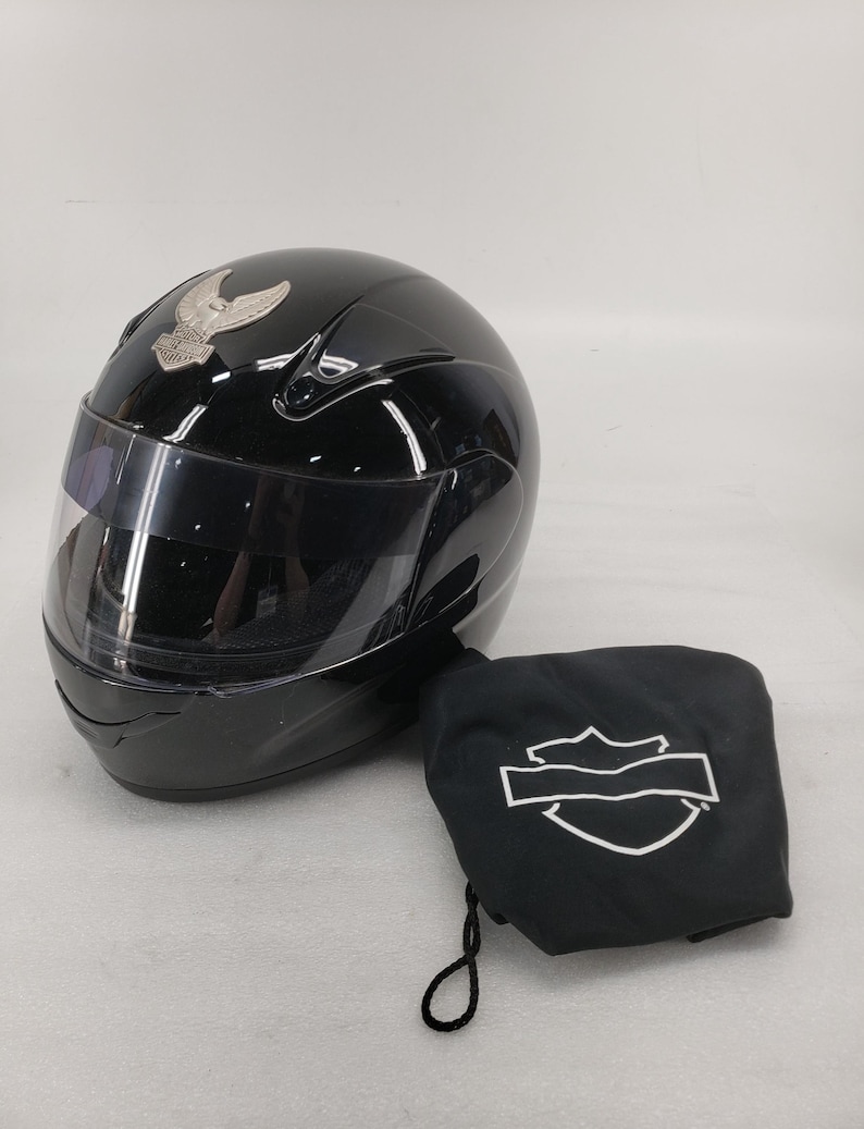 Peut inclure: Casque de moto noir brillant avec visi&egrave;re transparente et embl&egrave;me argent&eacute;. Comprend un sac de rangement noir avec un logo blanc. Le casque est con&ccedil;u pour la s&eacute;curit&eacute;.