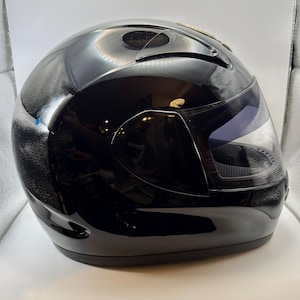 Peut inclure: Un casque de moto noir brillant avec une visi&egrave;re transparente. Le casque a un design &eacute;pur&eacute; avec des a&eacute;rations et une section de visi&egrave;re teint&eacute;e fonc&eacute;e. Le casque est con&ccedil;u pour la s&eacute;curit&eacute; et la protection.