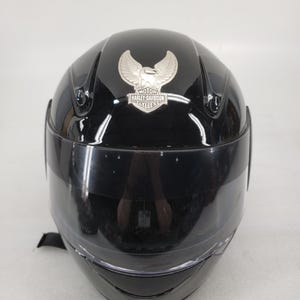 Peut inclure: Casque de moto noir avec une visi&egrave;re transparente. Le logo Harley-Davidson argent&eacute; est affich&eacute; &agrave; l'avant. Le casque a une finition brillante et un design &eacute;pur&eacute;.