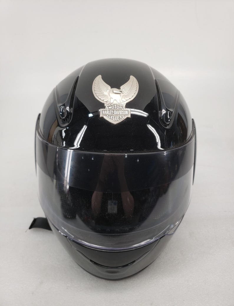 Peut inclure: Casque de moto noir avec une visi&egrave;re transparente. Le logo Harley-Davidson argent&eacute; est affich&eacute; &agrave; l'avant. Le casque a une finition brillante et un design &eacute;pur&eacute;.