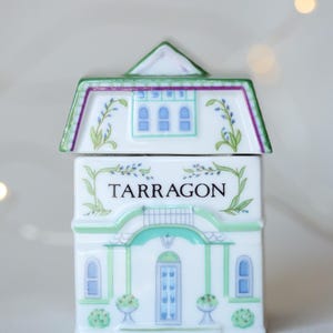K&ouml;nnte beinhalten: Weisses Keramik-Gew&uuml;rzgef&auml;ss in Form eines Hauses mit gr&uuml;nem Rahmen und blauen Fenstern. Das Gef&auml;ss tr&auml;gt die Aufschrift "TARRAGON" auf der Vorderseite.