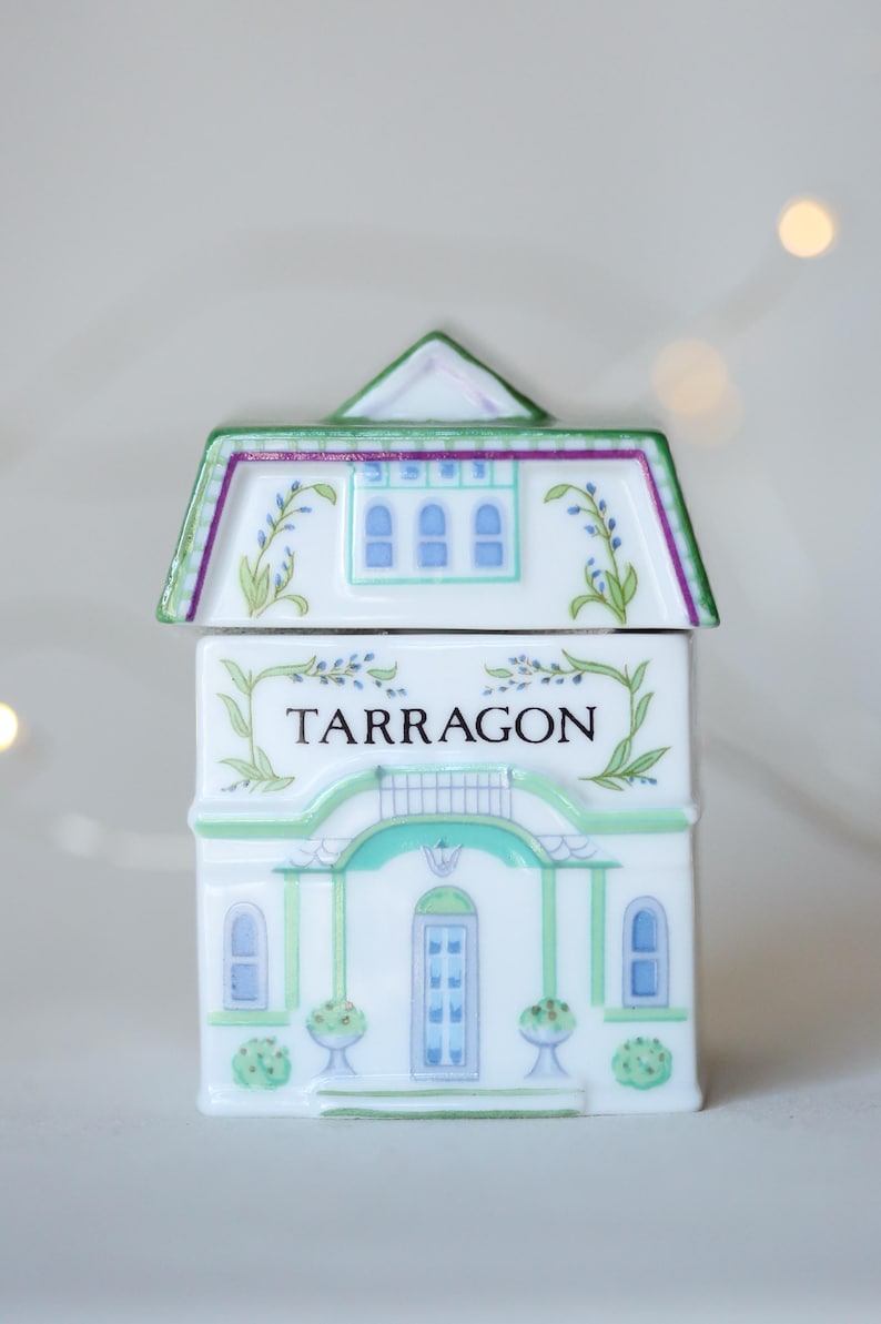 K&ouml;nnte beinhalten: Weisses Keramik-Gew&uuml;rzgef&auml;ss in Form eines Hauses mit gr&uuml;nem Rahmen und blauen Fenstern. Das Gef&auml;ss tr&auml;gt die Aufschrift "TARRAGON" auf der Vorderseite.
