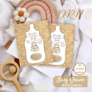 May include: A set of two baby shower bottle opener favors. Each favor features a white card shaped like a baby bottle with a brown and white dress hanging from a clothesline. The text on the card reads "Thank You for Celebrating with Us Emily". The cards are on a brown background with a damask pattern.