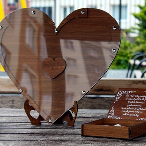 May include: A heart-shaped wooden box with a clear glass lid, a small wooden heart with the words "Always & Forever" engraved on it, and a smaller wooden box with a white inscription on the lid. The boxes are on a wooden surface.