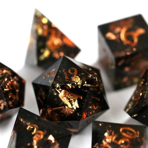 Brasa en las cenizas: dados DND negros con motas de oro y cobre