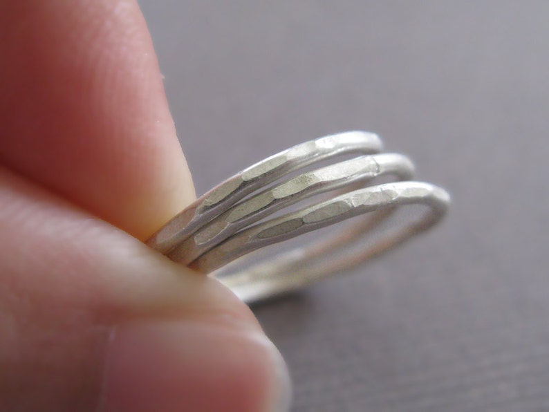Puede incluir: Tres anillos apilables de plata martillados. Los anillos son finos y tienen una superficie texturizada.