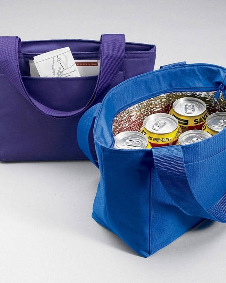K&ouml;nnte beinhalten: Zwei isolierte Lunch-Taschen, eine lila und eine blaue. Die blaue Tasche ist offen und enth&auml;lt mehrere Dosen Limonade. Die Taschen haben einen Rei&szlig;verschluss und einen oberen Griff.