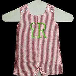 May include: Red and white striped baby overalls with a green embroidered monogram "LR" on the front.