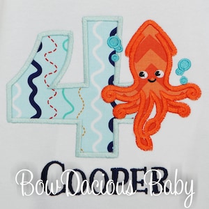May include: A blue and white embroidered number four with a red and orange octopus with a smiling face and blue bubbles. The text "Bow Dacious Baby" is embroidered below the number.