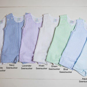 May include: Ten sleeveless baby onesies in various colors with white stripes. The colors are red, white, navy, lavender, khaki, green, blue, and aqua.