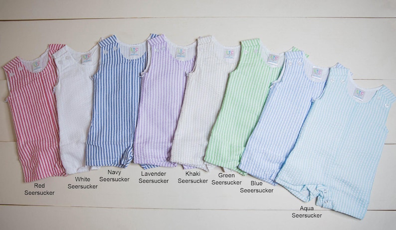 May include: Ten sleeveless baby onesies in various colors with white stripes. The colors are red, white, navy, lavender, khaki, green, blue, and aqua.