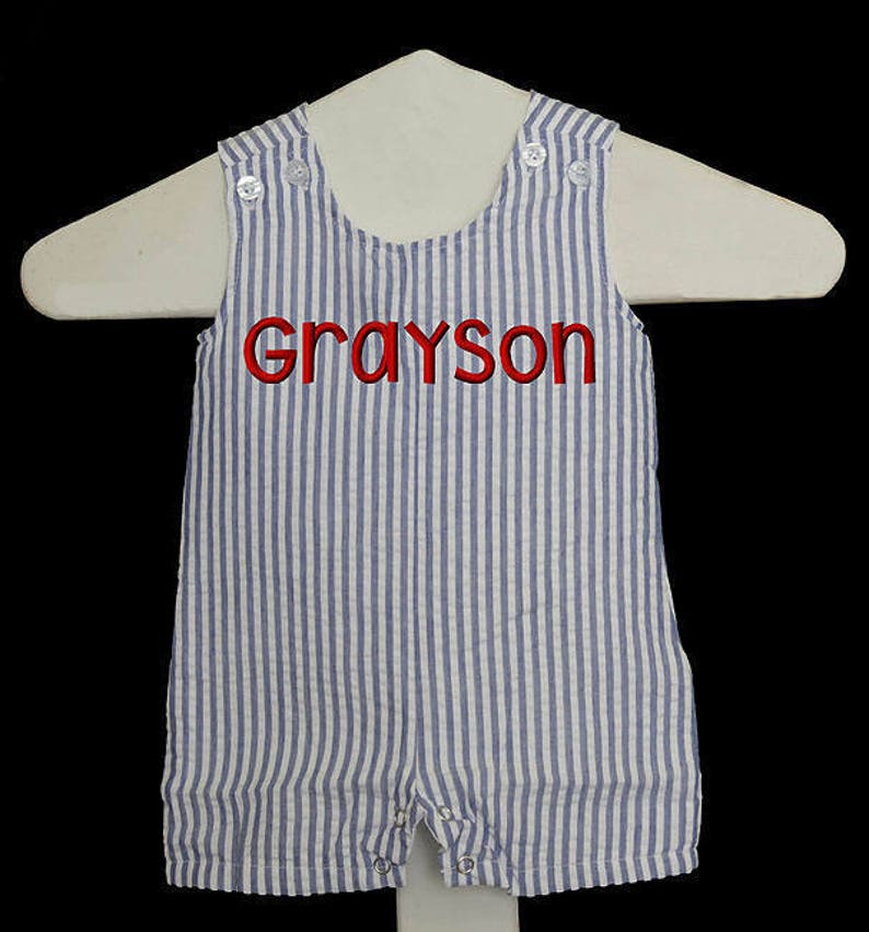 May include: Blue and white striped baby overalls with the name Grayson embroidered in red.