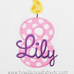 May include: Pink and white polka dot number eight candle with a yellow flame and the name "Lily" in purple cursive.