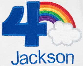 May include: White garment with a large blue number 4, a rainbow, and a cloud. The name "Jackson" is embroidered in blue below the number. The rainbow features red, orange, yellow, green, blue, and purple. The cloud is white with a gray outline.