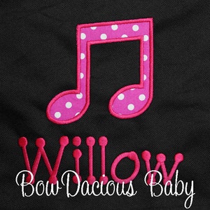 May include: Pink musical note with white polka dots and the text "Willow Bow Dacious Baby" in pink.