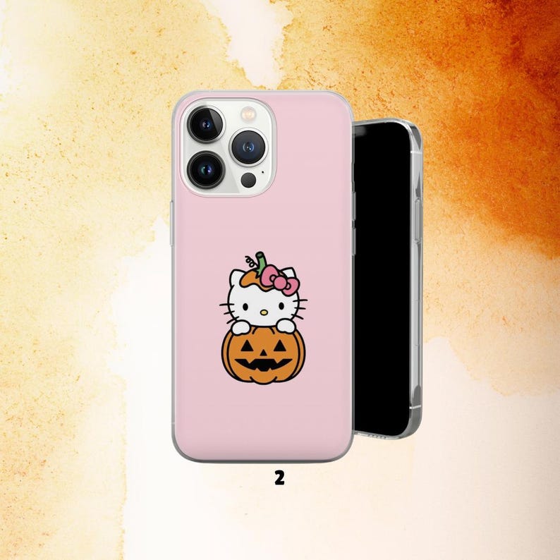 Puede incluir: Una funda de tel&eacute;fono rosa con un personaje de gato de dibujos animados con un lazo rosa, sentado sobre una calabaza naranja tallada. Un tel&eacute;fono inteligente negro est&aacute; al lado de la funda. El n&uacute;mero "2" est&aacute; impreso en la parte inferior.