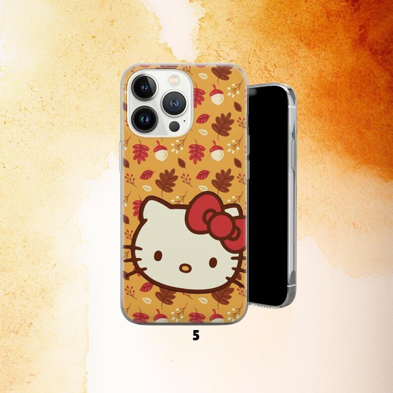 Puede incluir: Una funda transparente para tel&eacute;fono con un gato de dibujos animados y un lazo rojo, sobre un fondo amarillo con hojas de oto&ntilde;o y bellotas. El n&uacute;mero 5 est&aacute; impreso en la parte inferior. Un smartphone negro est&aacute; al lado de la funda.