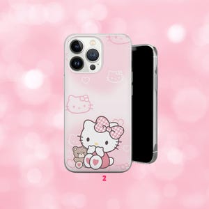 May include: A pink phone case featuring a cartoon cat with a pink bow and a teddy bear. The case has a repeating pattern of cat faces and hearts. The number "2" is printed at the bottom.