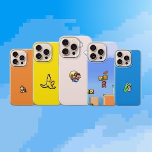 May include: Five colorful phone cases with pixelated designs. The cases are orange, yellow, off-white, light blue, and blue. Each case features a different graphic, including a monkey, banana, Mario, and a frog.