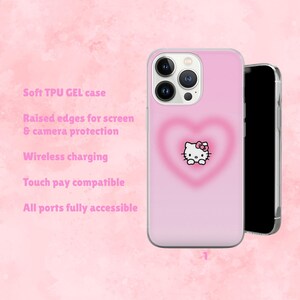 Puede incluir: Una funda de tel&eacute;fono rosa con un dise&ntilde;o de Hello Kitty dentro de un gr&aacute;fico en forma de coraz&oacute;n. La funda tiene bordes elevados para la protecci&oacute;n de la pantalla y la c&aacute;mara. El texto en la funda dice: Soft TPU GEL case, Wireless charging, Touch pay compatible, y All ports fully accessible.