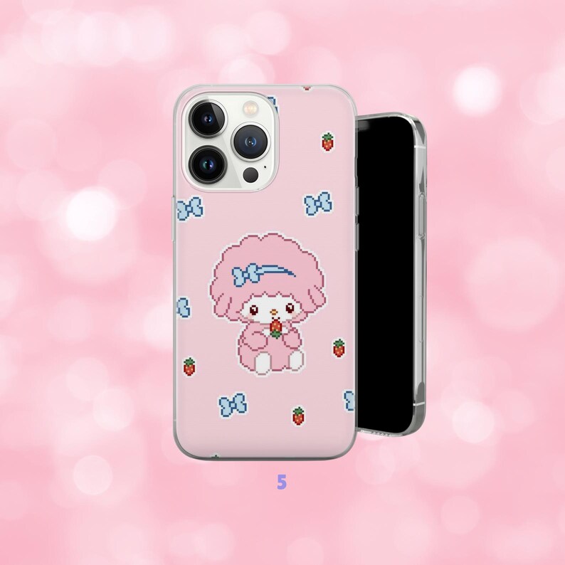 May include: Pink phone case featuring a cartoon character with a blue bow and holding a strawberry. The case has a pixelated design with blue bows and strawberries scattered across the surface. A black smartphone is next to the case.