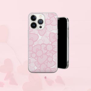 Puede incluir: Funda transparente para tel&eacute;fono con un dise&ntilde;o de lazo rosa. Los lazos tienen forma de coraz&oacute;n y lunares. Un smartphone negro est&aacute; al lado.