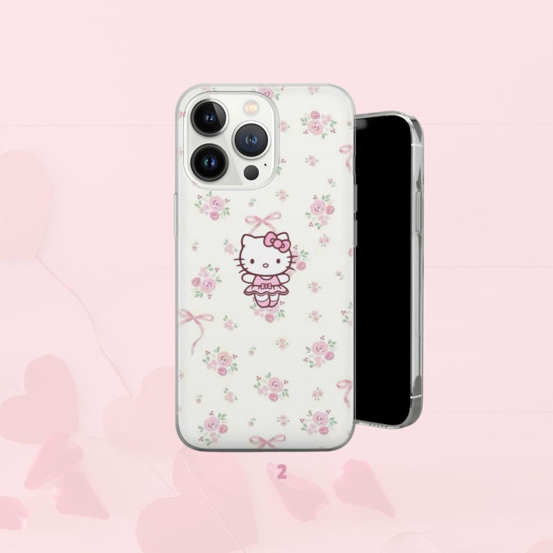 Puede incluir: Una funda transparente para tel&eacute;fono con un estampado floral blanco y un gr&aacute;fico de Hello Kitty. La funda presenta un lazo rosa y un vestido rosa en el personaje. La funda del tel&eacute;fono est&aacute; al lado de un tel&eacute;fono inteligente negro.